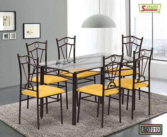 Modern glass dining table set with six metal chairs, yellow cushions, in a bright room Main image