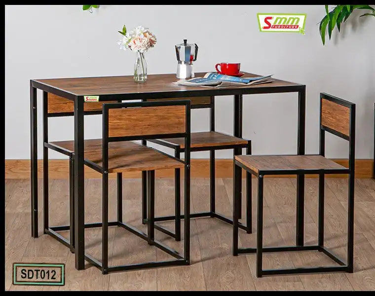 Modern dining table set with four wooden chairs and metal frames, tabletop decor including flowers, coffee cup and moka pot, on wooden floor.