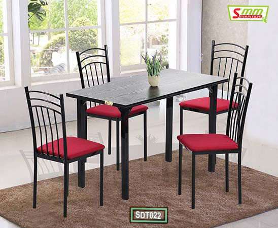 Modern black dining table with four chairs featuring red cushions, set on a brown rug in a bright room Main image