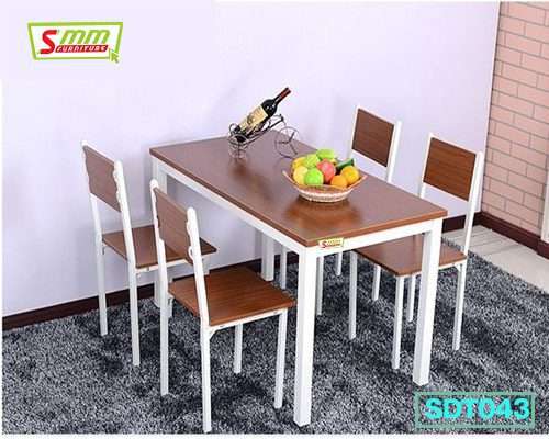 Wooden dining table set with four chairs, fruit bowl, and wine bottle on a gray rug Main image