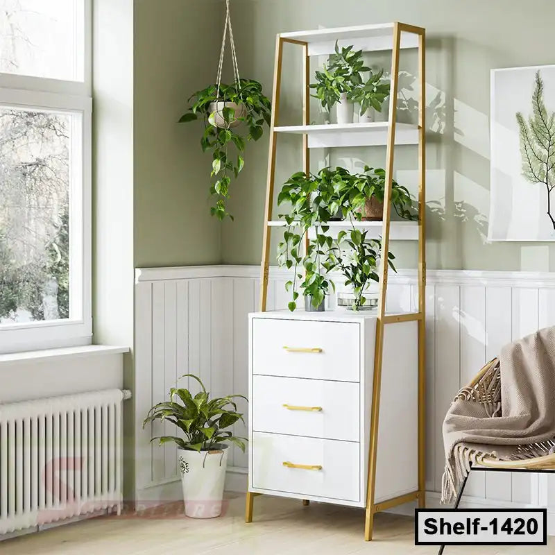 Modern white and gold standing shelf with houseplants, three drawers, beside a window in a cozy home interior.