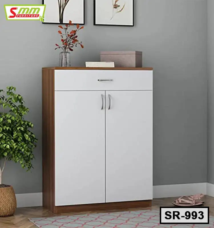 Modern wooden shoe rack with white doors and drawer in a home entryway, indoor plant beside it Main image