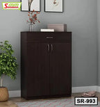 Modern dark wood shoe rack cabinet with two doors, drawer, and plants in a home interior
