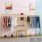 Modern gold metal standing closet organizer with shelves for clothes and shoes in a room