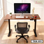 Standing desk with black chair, computer, and office accessories in a bright workspace