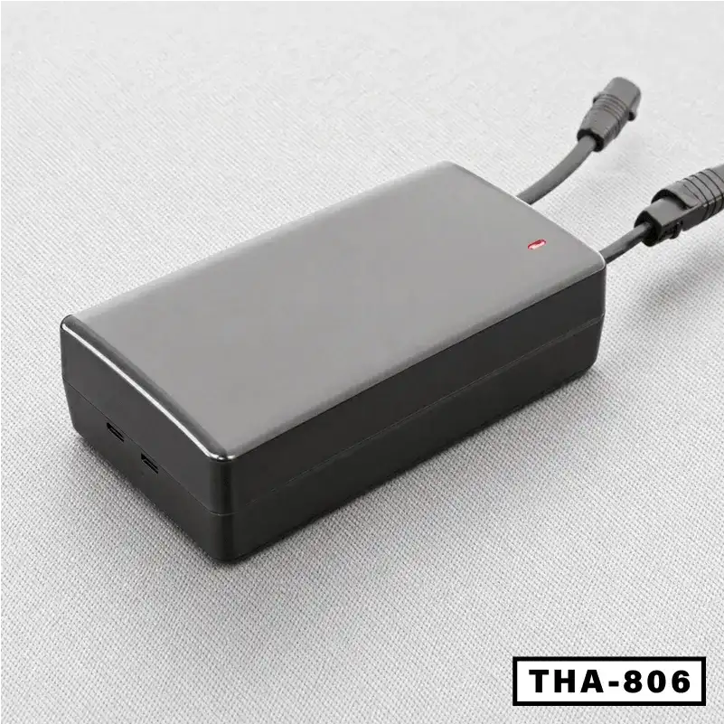 Black power adapter with dual cables for standing desk on light gray surface, THA-806 label