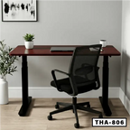 Standing computer desk with dark wood top, black frame, office chair, and potted plant