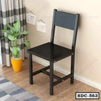 Modern black steel dining chair in a living room with a plant and wooden flooring