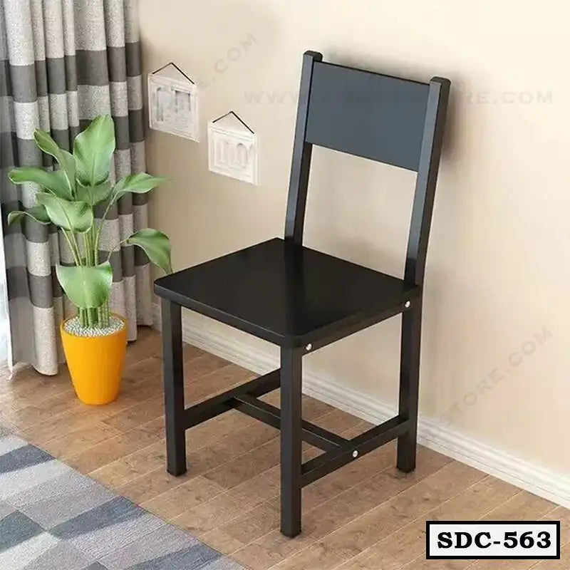 Modern black steel dining chair in a living room with a plant and wooden flooring