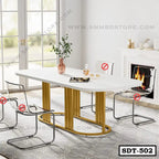 Modern steel dining table with gold base and white top in a bright dining room with transparent chairs