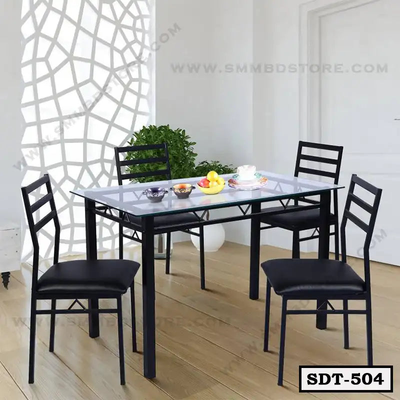 Modern steel dining table set with glass top and four black chairs in a bright dining room