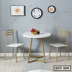 Modern steel dining table set with two white chairs and gold frames in a minimalist room