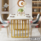 Modern steel dining table with gold frame, white top, and upholstered chairs in a stylish room