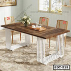 Modern steel dining table with a wooden top and white metal legs, set with flowers and tea set.