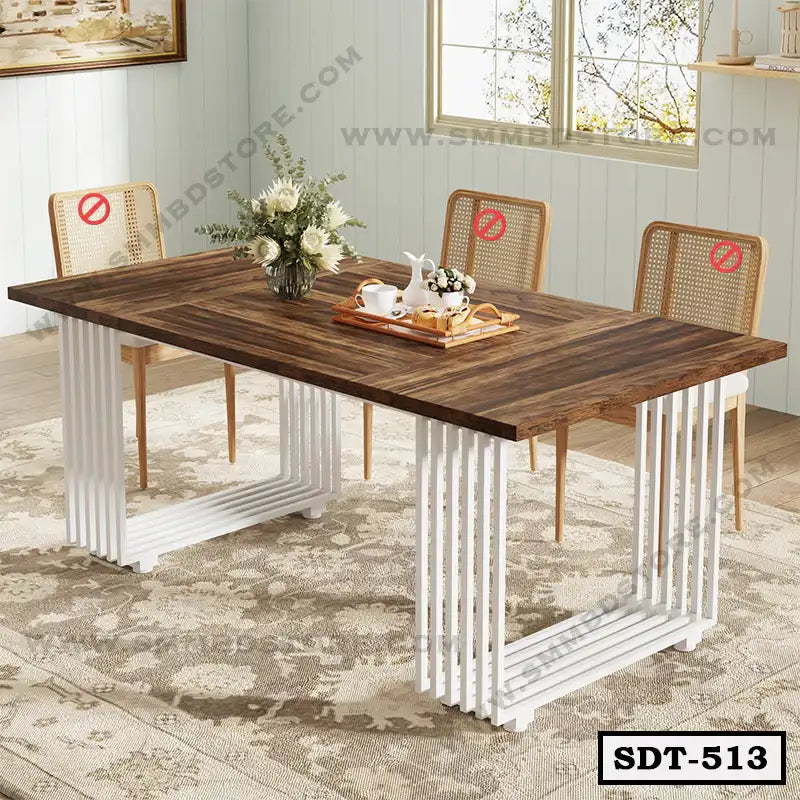 Modern steel dining table with a wooden top and white metal legs, set with flowers and tea set.