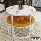 Modern round steel dining table with white marble top and four yellow cushioned stools