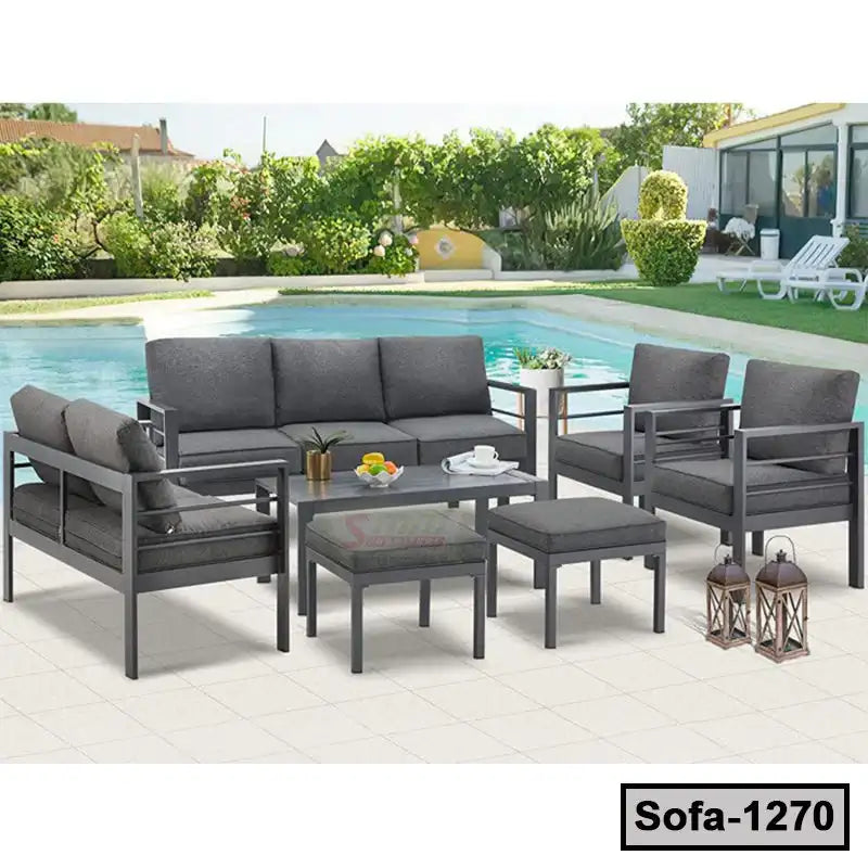 Modern grey steel outdoor sofa set with cushions and table by a swimming pool