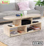 Modern wood tea table with open shelving, books, mug, and remotes in a living room
