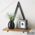 Modern wall shelf with black metal frame, wood base, plant in vase, and small photo frame