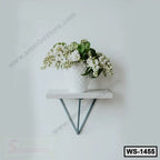 Modern wall shelf with metal brackets holding a white vase of flowers on a light wall