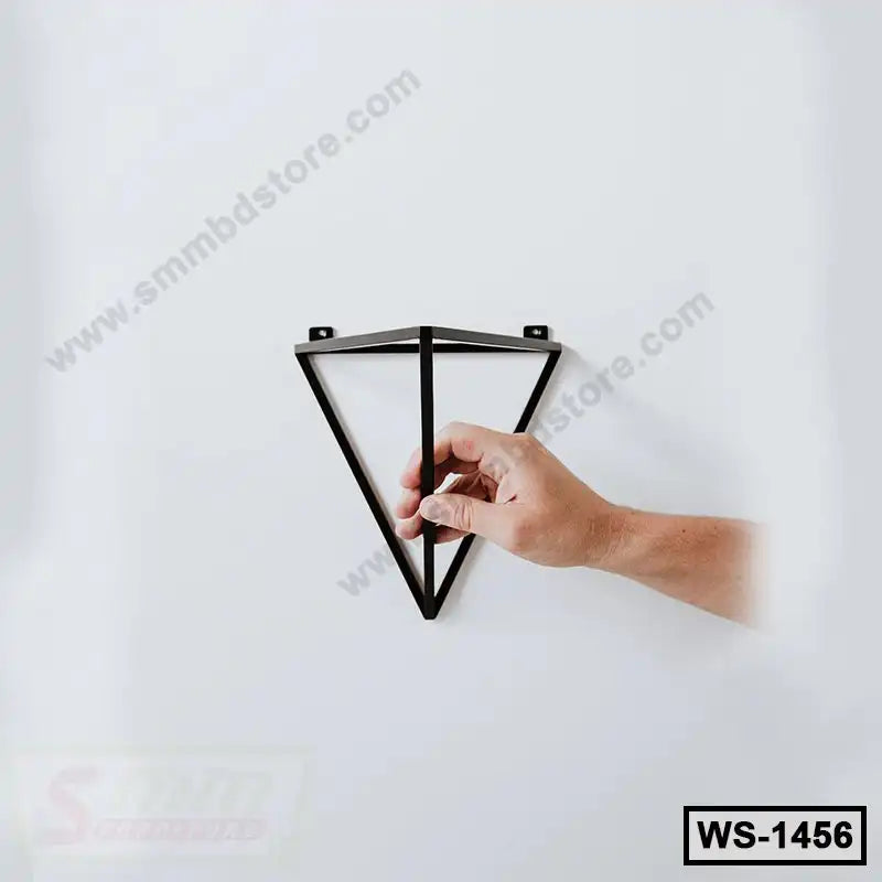 Hand mounting a modern black metal triangle wall shelf on a white wall