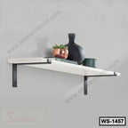 Modern wall shelf with metal brackets, decorative vase, plant, and books on a grey wall.