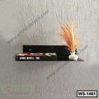 Modern black wall shelf mounted on textured gray wall with book and decorative vase