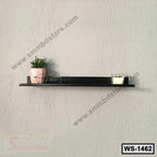 Modern wall shelf with small plant, glasses, and candle on a textured grey wall