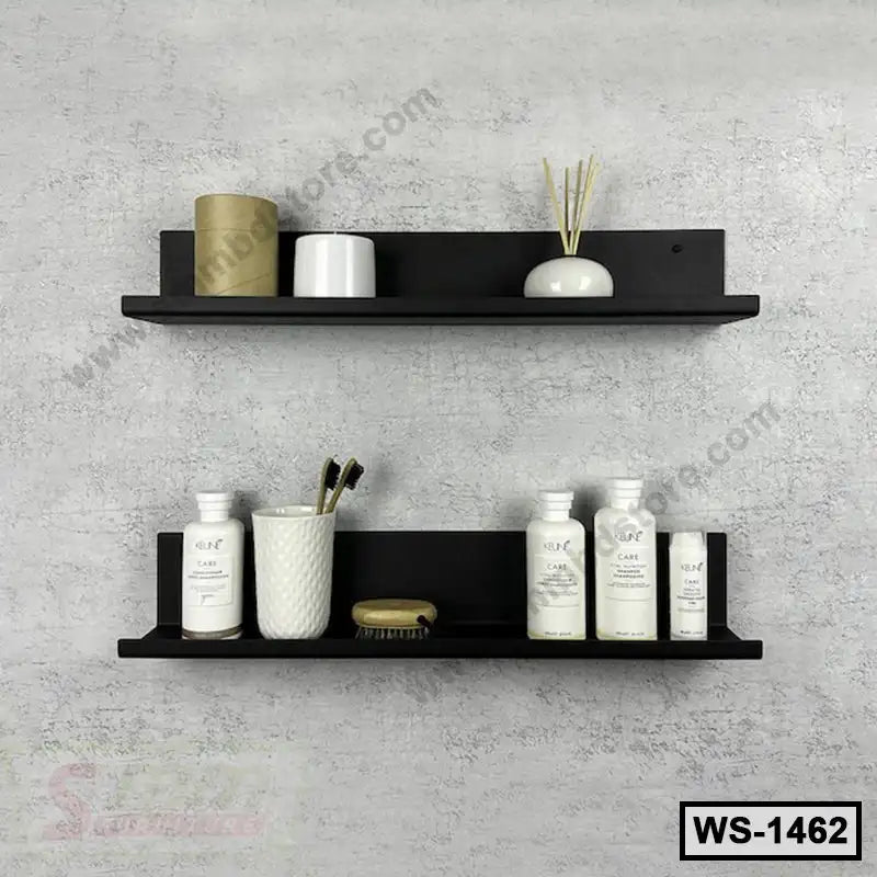 Modern black wall shelves mounted on a light grey wall holding bathroom accessories and decor.