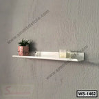 Modern white wall shelf with potted plant, candles, and eyeglasses against a gray wall