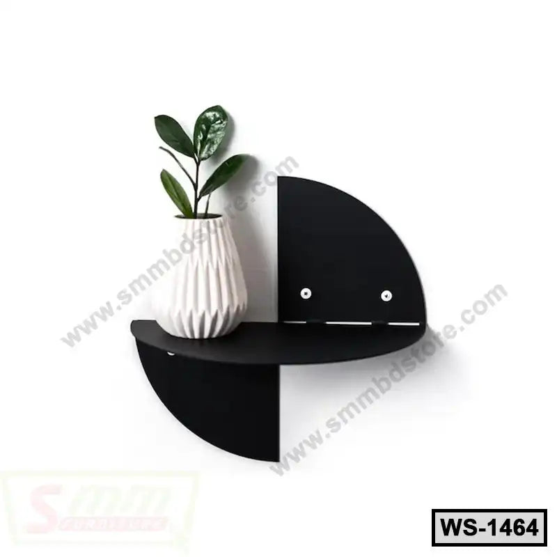 Modern black wall shelf with geometric design, holding a white vase with green plant.