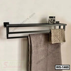 Wall-mounted metal towel rack with shelf, holding towels and jar on white wall
