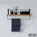 Modern wall shelf with wooden plank, metal frame, black towel, and toiletries on white wall.
