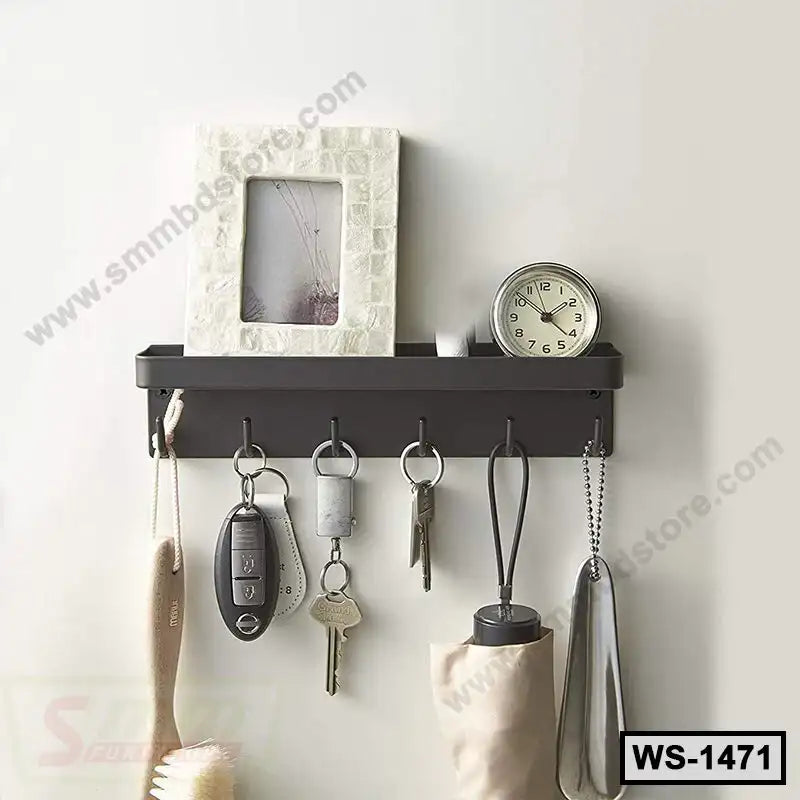 Wall-mounted black storage shelf with hooks holding keys and accessories, clock and photo frame on top.