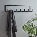 Modern black wall shelf with six hooks, holding a gray towel, indoor plant nearby