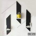 Set of three modern black wall shelves with white accents, one holding a yellow potted plant
