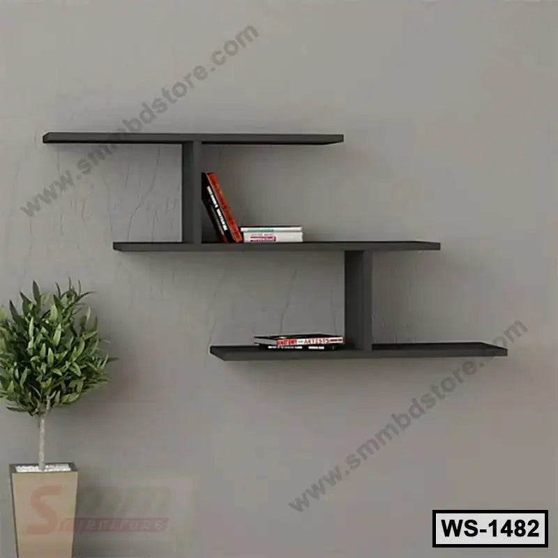 Modern black wall shelf with books, mounted on grey wall above potted plant