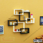 Modern geometric wall shelf with black and white open shelves, decorated with small home decor items, mounted on a yellow wall.