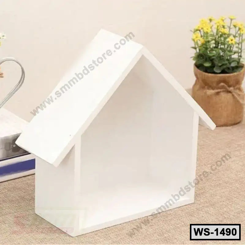 White house-shaped wooden wall shelf on a table with books and a potted plant