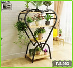 Heart-shaped metal plant stand with wooden shelves displaying potted indoor plants