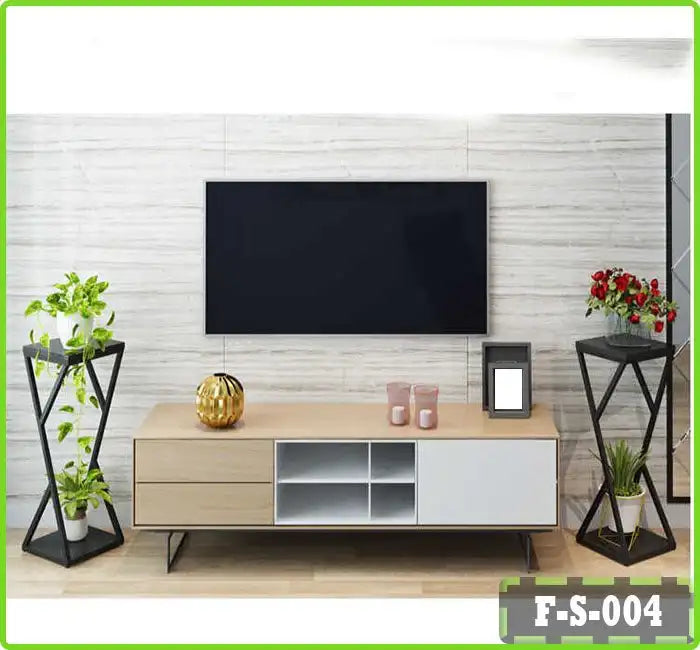 Modern living room with wall-mounted TV, light wood TV console, indoor plants, and decorative items.